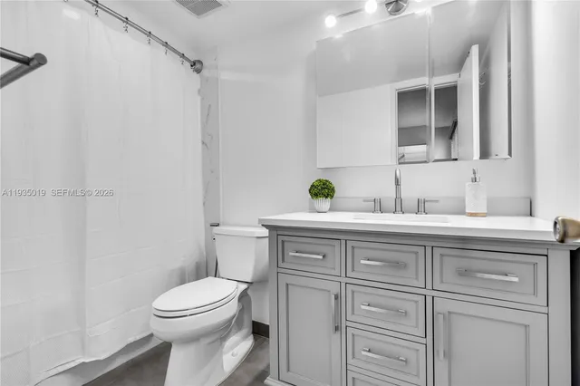 a bathroom with a granite countertop toilet sink and mirror