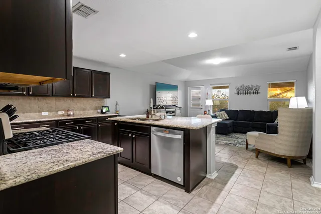 a kitchen with stainless steel appliances granite countertop a sink a stove a counter space and cabinets