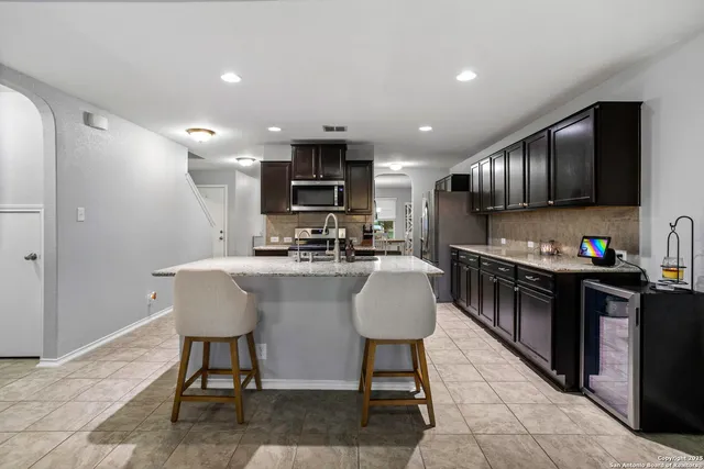 a kitchen with kitchen island granite countertop a sink a stove a refrigerator cabinets and a dining table with wooden floor