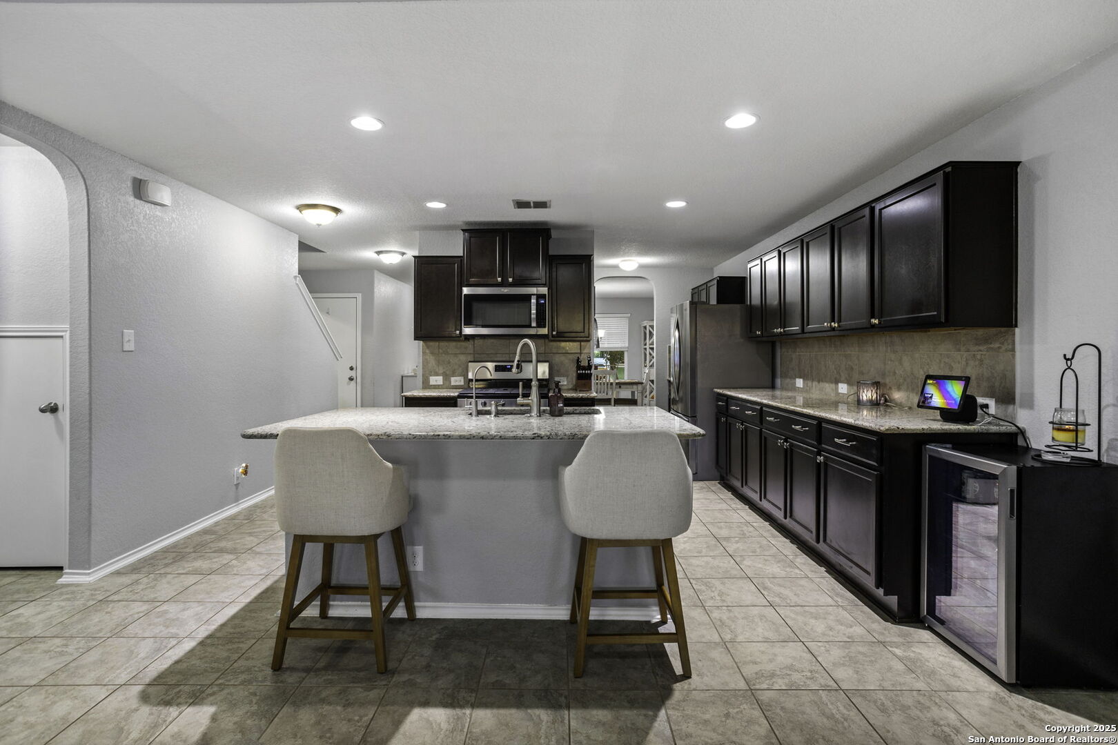 212 Kildeer Creek San Antonio, TX 78253 - Photo 8 of 29 a kitchen with kitchen island granite countertop a sink a stove a refrigerator cabinets and a dining table with wooden floor