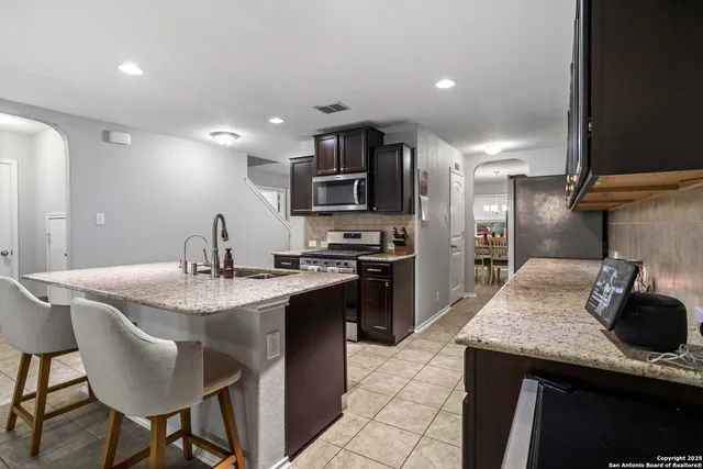 a kitchen with kitchen island granite countertop a sink and stainless steel appliances