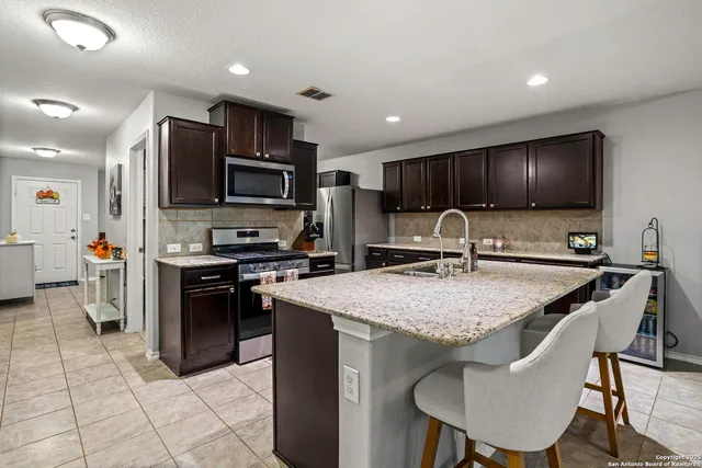 a kitchen with stainless steel appliances granite countertop a sink refrigerator and cabinets