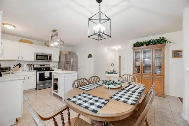a dining room with wooden floor a chandelier a wooden table and chairs