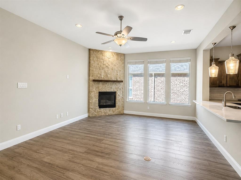 6209 Cupleaf Road Flower Mound, TX 76226 - Photo 6 of 29 Living area featuring wood-finish flooring, a corner fireplace with stone surround and wood mantel, recessed lighting, and a ceiling fan