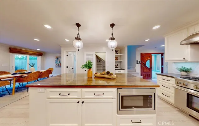 a large kitchen with granite countertop lots of counter space wooden floor and stainless steel appliances