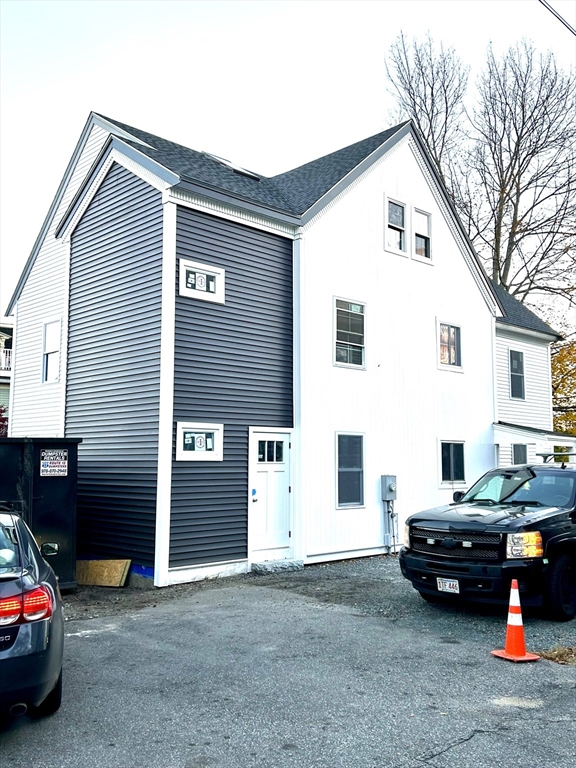 a view of a house with a cars park side of a road
