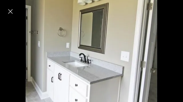 a bathroom with a granite countertop sink and a mirror