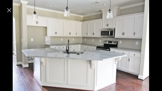 a kitchen with stainless steel appliances granite countertop a sink a stove a refrigerator and white cabinets with wooden floor