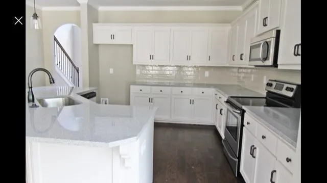 a kitchen with granite countertop a sink a stove and cabinets