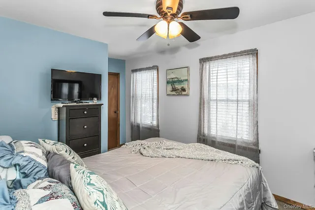 a bedroom with a bed and a flat tv screen on dresser