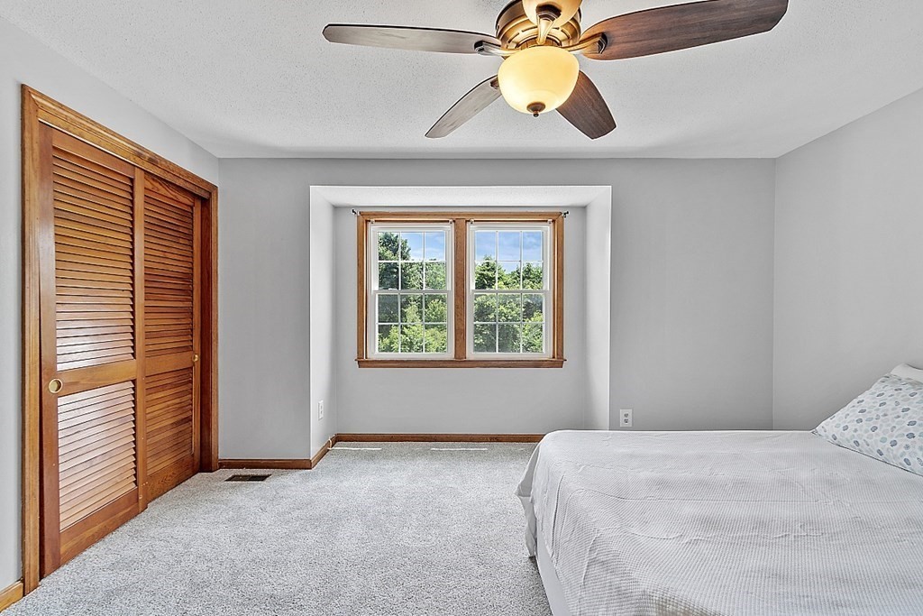 25 Juniper Place, Unit 9 Lowell, MA 01852 - Photo 23 of 42 a bedroom with a bed and a chandelier