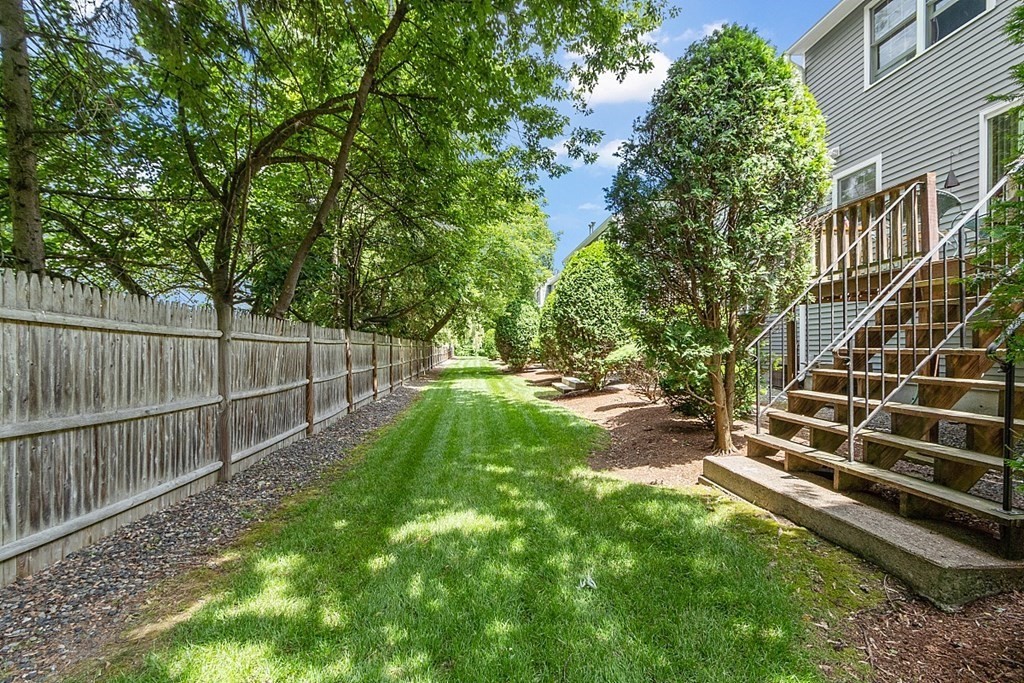 25 Juniper Place, Unit 9 Lowell, MA 01852 - Photo 37 of 42 a view of a yard with large trees and a wooden fence