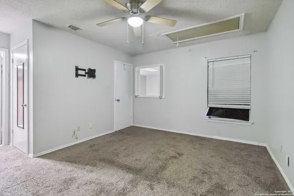 an empty room with a ceiling fan and a window