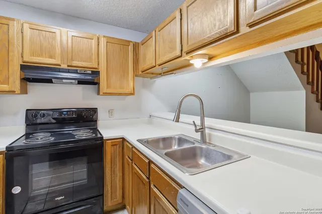 a kitchen with granite countertop a sink a stove and cabinets