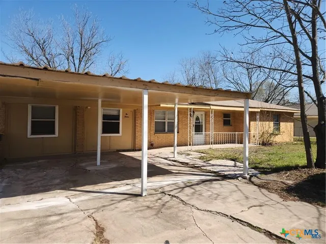 a view of a house with a yard and large tree