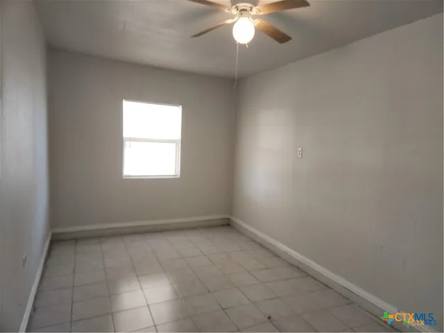 an empty room with a chandelier fan and windows
