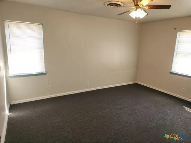 an empty room with a window and a fan