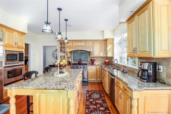 a kitchen with stainless steel appliances granite countertop a sink a stove and a wooden cabinets