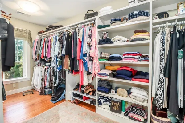 a view of walk in closet with clothes and shoes