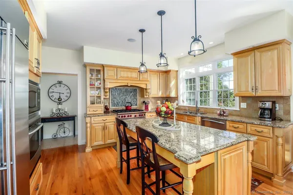a open kitchen with stainless steel appliances granite countertop a stove a sink dishwasher a dining table and chairs with wooden floor