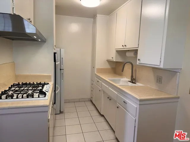 a kitchen with white cabinets a sink and appliances