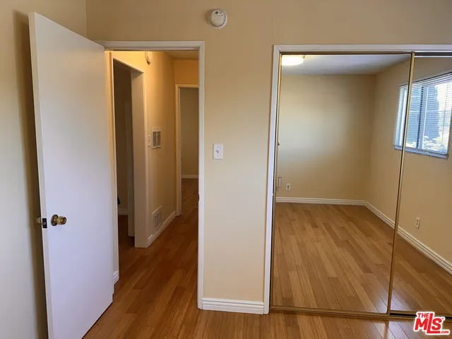 a view of a hallway with wooden floor and closet