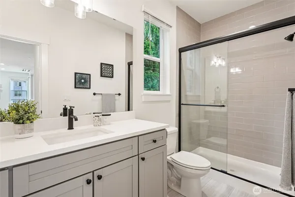 a bathroom with a sink a toilet a mirror and shower