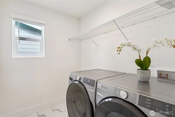 a utility room with dryer and potted plants