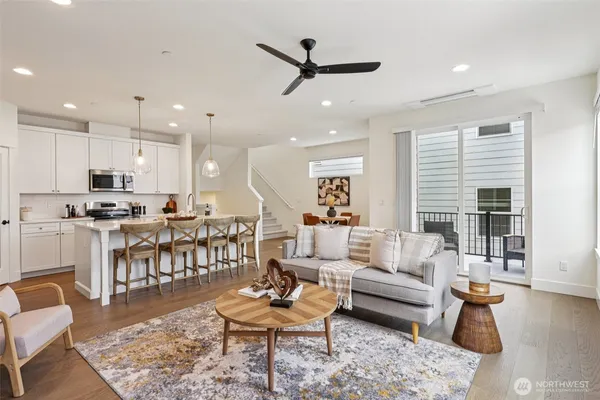 a living room with furniture kitchen view and a wooden floor