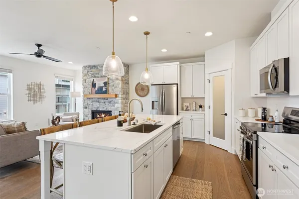 a kitchen that has a lot of white cabinets and stainless steel appliances