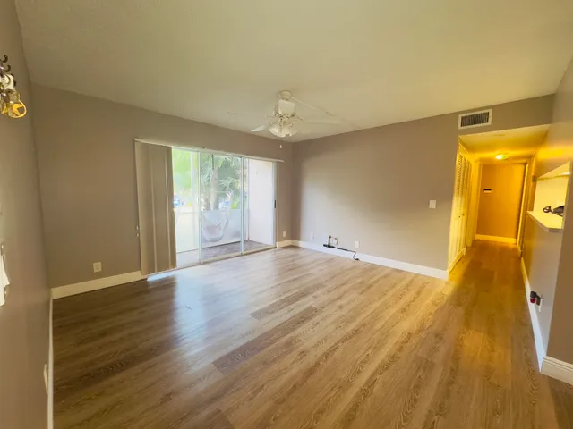 a view of empty room with wooden floor and fan