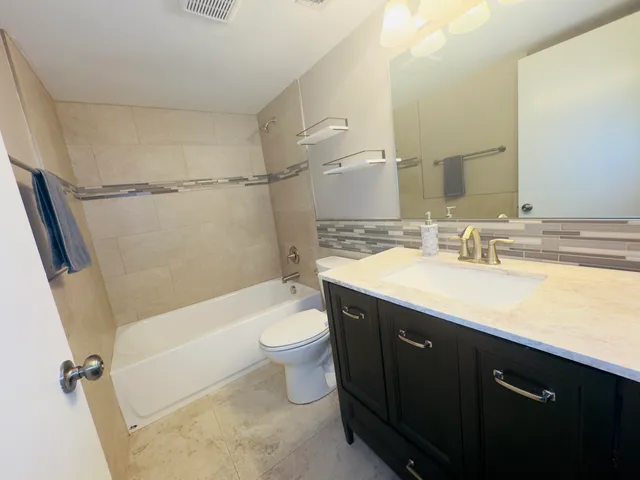 a bathroom with a double vanity sink toilet mirror and bathtub