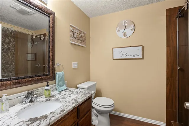 a bathroom with a granite countertop sink mirror vanity and toilet