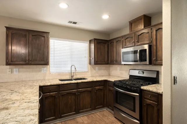 a kitchen with granite countertop stainless steel appliances a sink stove top oven and microwave
