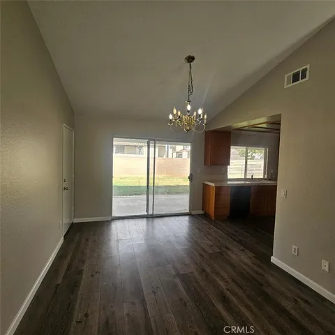 a view of a room with wooden floor chandelier and kitchen