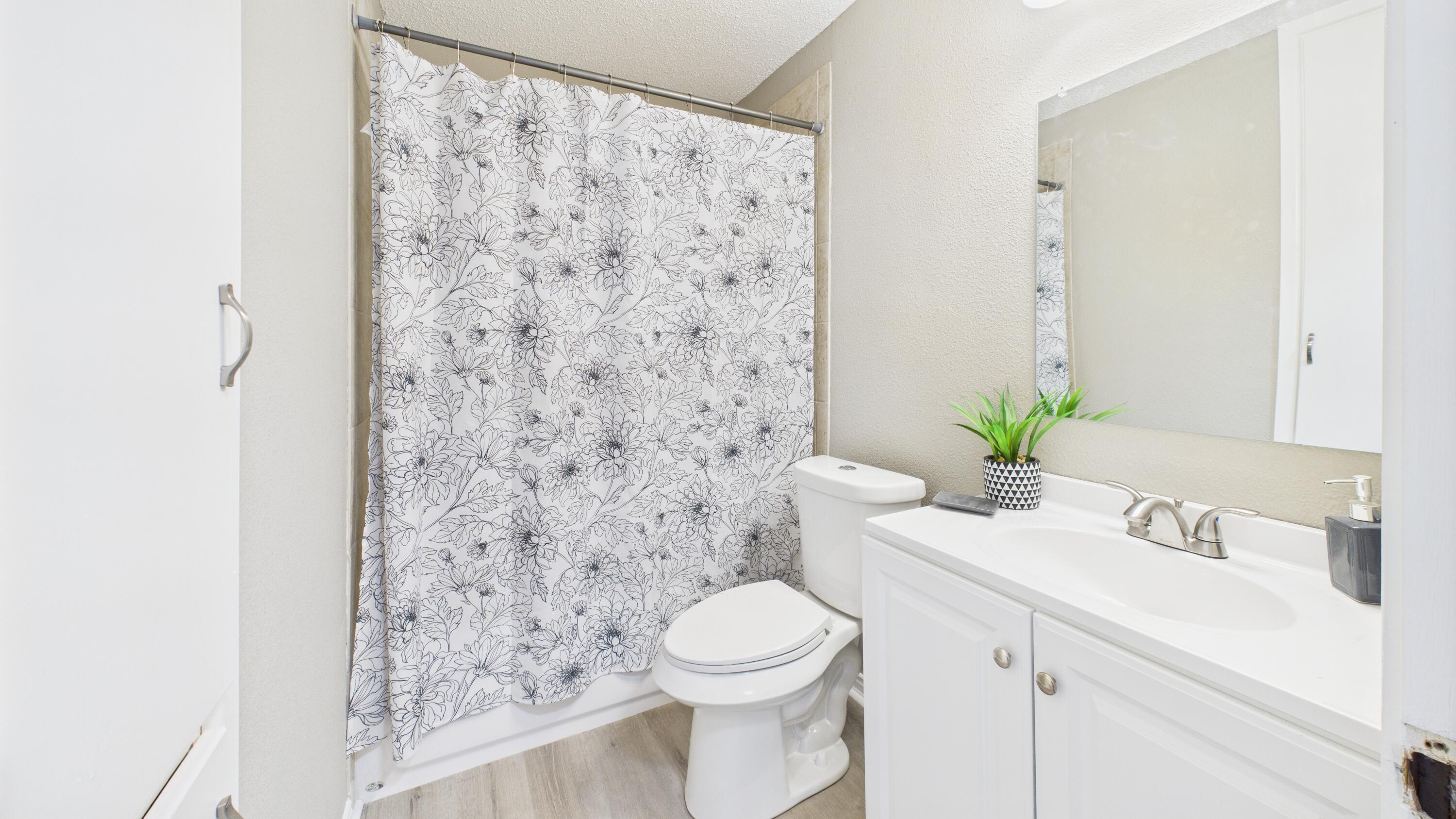 5719 2nd Street Lubbock, TX 79416 - Photo 33 of 61 a bathroom with a sink a toilet and shower curtain