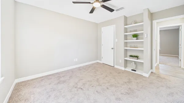 an empty room with a window and a fan