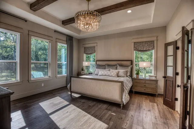 a bedroom with a large bed and a chandelier next to a window
