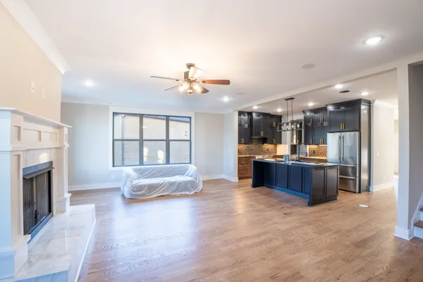 a large living room with stainless steel appliances kitchen island granite countertop a large window and a kitchen view