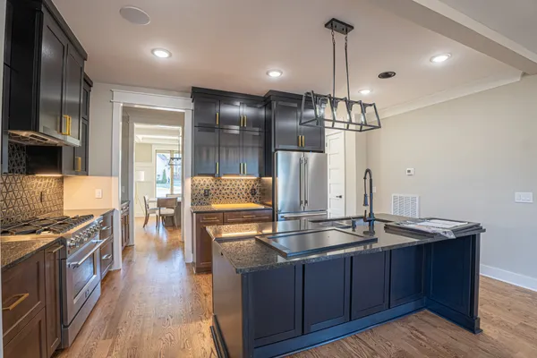 a kitchen with stainless steel appliances granite countertop a refrigerator a stove and a sink with wooden floor