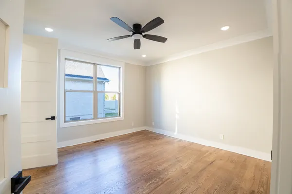 a view of empty room with wooden floor and fan
