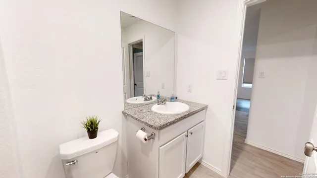 a bathroom with a granite countertop sink and a toilet