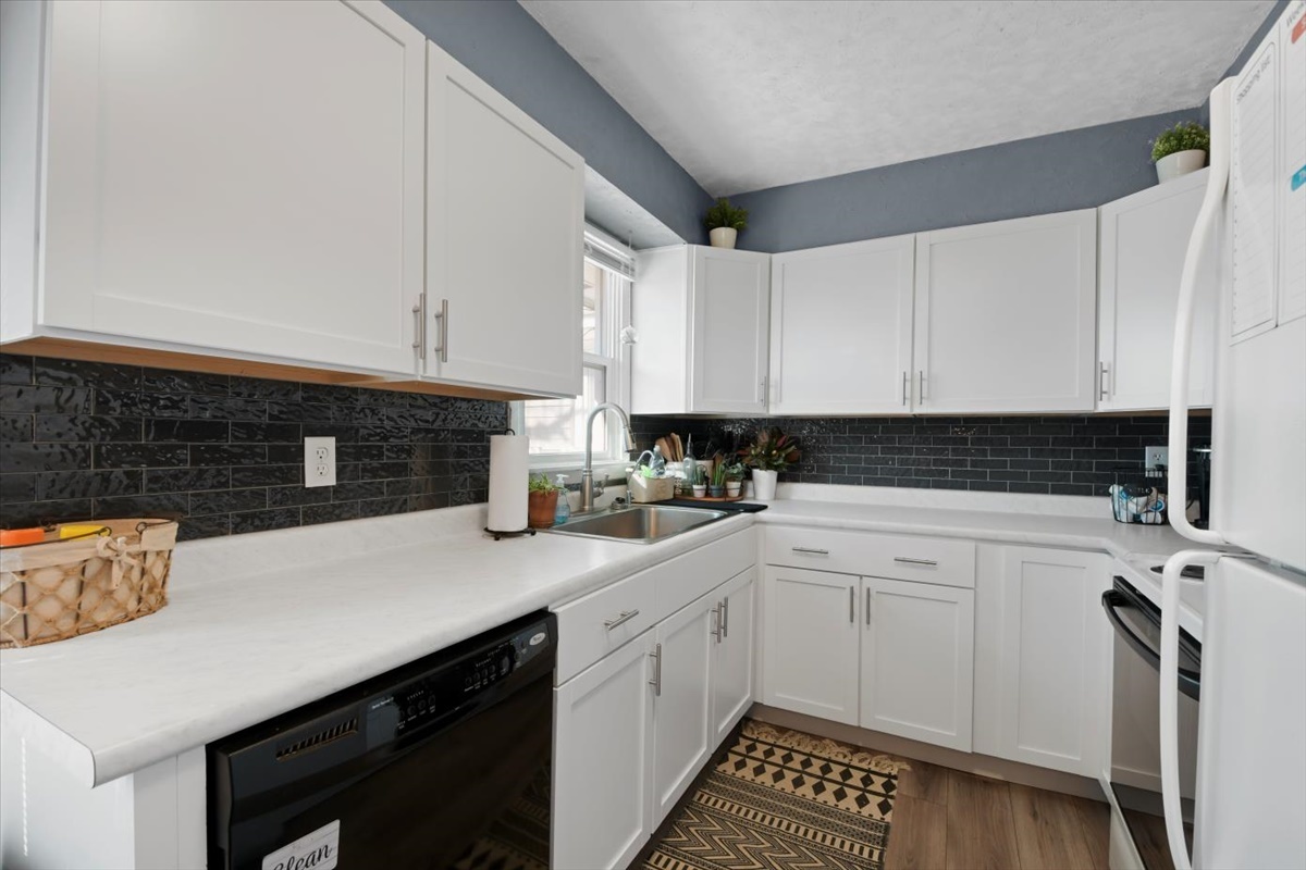 215 North 3rd Street Fisher, IL 61843 - Photo 5 of 17 a kitchen with a sink dishwasher a stove and white cabinets with wooden floor
