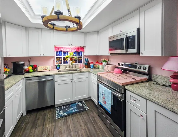 a kitchen with stainless steel appliances granite countertop a sink dishwasher stove and microwave with wooden floor
