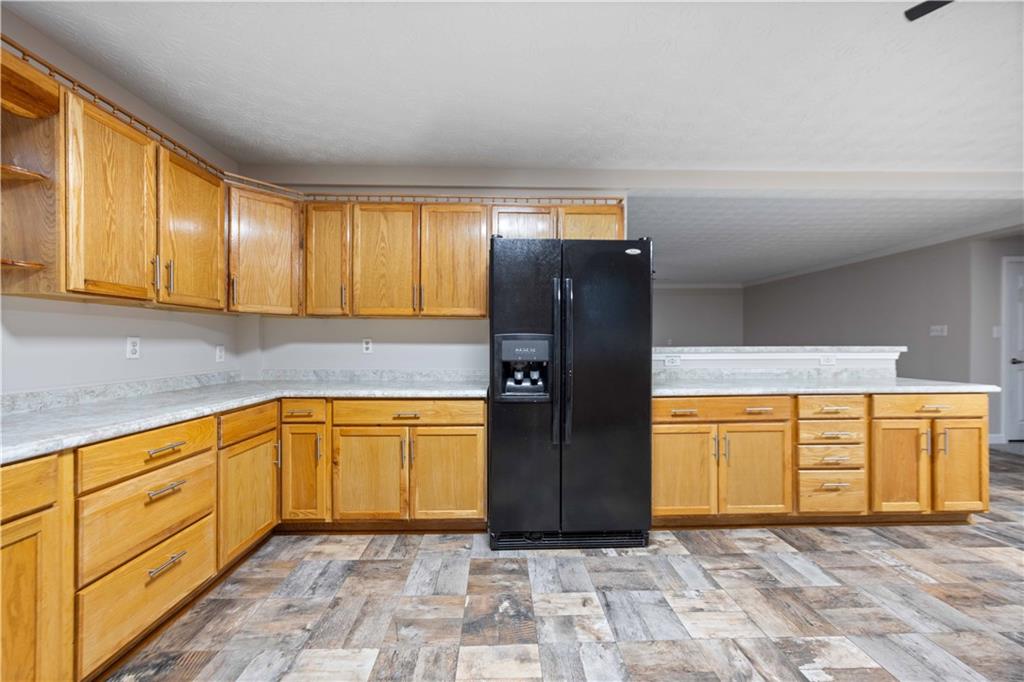 25 Gas Line Road Phenix City, AL 36870 - Photo 10 of 52 Kitchen featuring black refrigerator with ice dispenser, open shelves, light countertops, a peninsula, and light stone finish flooring
