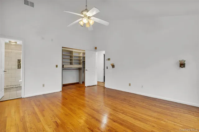 an empty room with wooden floor chandelier fan and windows