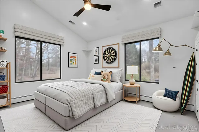 a bedroom with a bed couch painting on the wall and a large window