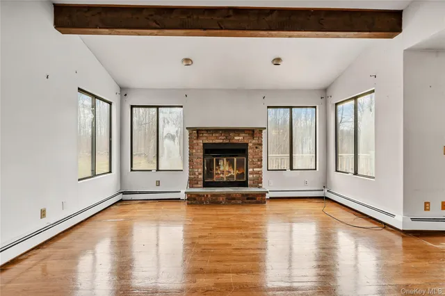 a view of an empty room with glass door and wooden floor