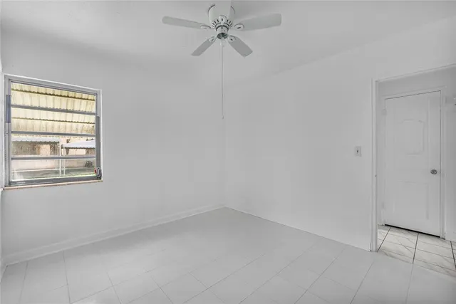 an empty room with a window and a ceiling fan