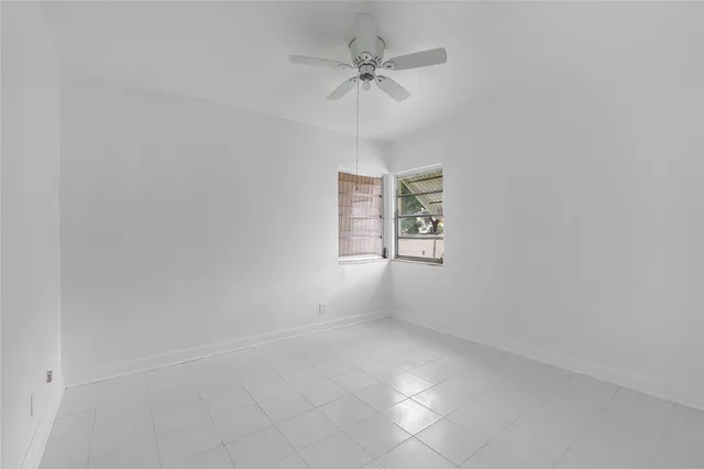 an empty room with white walls and ceiling fan